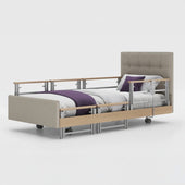 Profiling bed with side rails and wheels, white bedding and purple blanket, linen fabric finish, front view.
