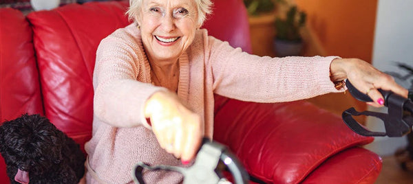Woman sitting on a red couch with a black dog, holding a rollator. Image