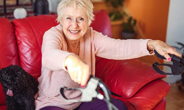 Woman sitting on a red couch with a black dog, holding a rollator.