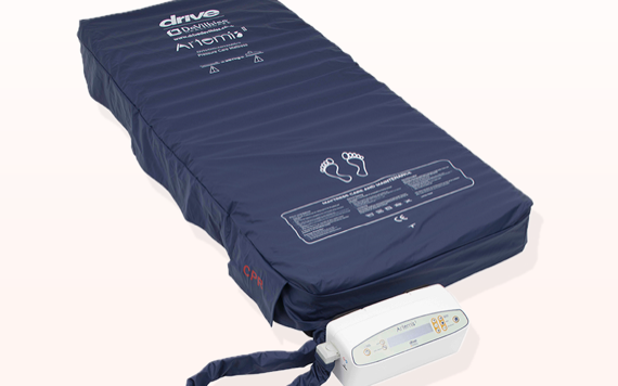 A medical air mattress with dark blue cover, featuring control panel and tubing on the side. The control panel displays settings.