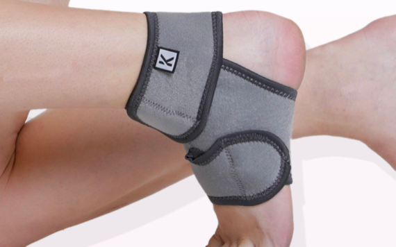 A close-up of a foot with a gray ankle brace that has adjustable Velcro straps and black edges, designed for support and comfort.