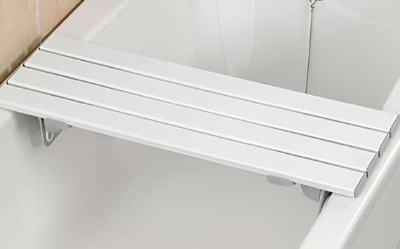 A white folding bathtub bench with slats, securely positioned across the bathtub for safe and sturdy seating.