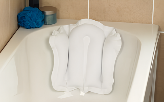 Inflatable white bath pillow attached to the back of a bathtub. A blue sponge and a small teal container are positioned on the tubs edge.