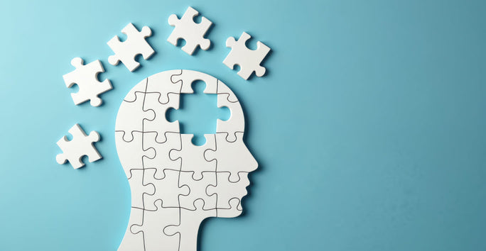 A human head silhouette made of white puzzle pieces on blue. One puzzle piece is missing from the top, with others floating above.