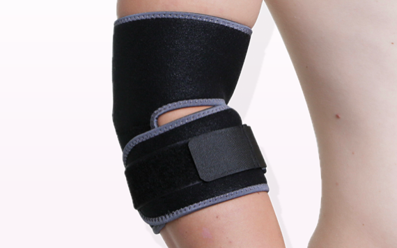 A person wears a black elbow brace with gray edges against a plain white background for support and stability.