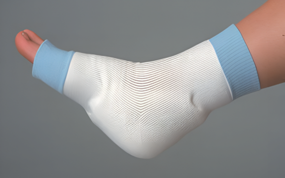 A foot wrapped in a white bandage with light blue ends, covering from toes to above the ankle. The background is neutral gray.