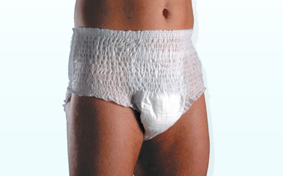 A person is wearing a white adult diaper with an elastic waistband and textured surface, standing against a light background.