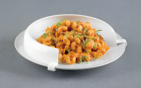 A plate of pasta with sprouts, and a white guard on the edge, on a grey surface.