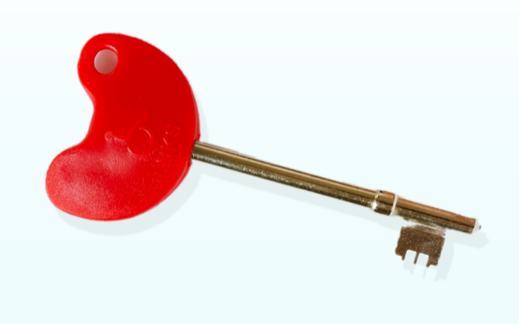 A silver key with a red, heart-shaped head and a small hole. The key lies horizontally on a plain white background.