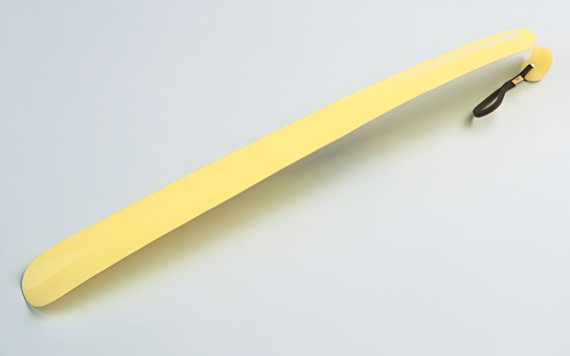A long, yellow, banana-shaped umbrella with a curved black handle, partially open, lying on a light gray surface.