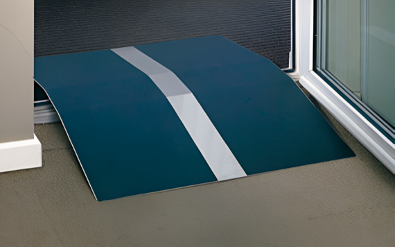 A small, portable blue wheelchair ramp with a white stripe is positioned at the threshold of a doorway for easy access.