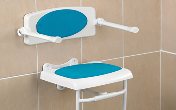 A shower seat with blue cushions and armrests is mounted on beige tiled walls for comfort and accessibility.