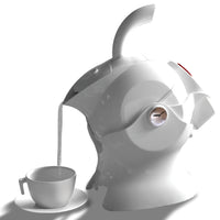 White Uccello Designs kettle with ergonomic handle pouring into a teacup on white surface, side view.