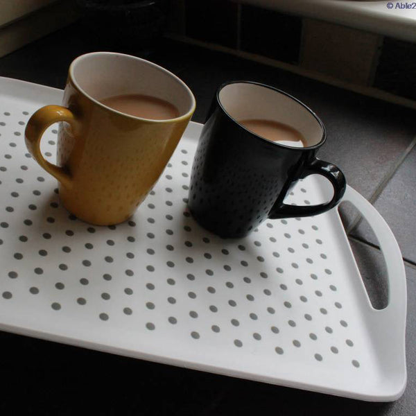 Able2 Stayput Anti-Slip Tray with yellow and black mugs of tea on a dark kitchen counter, in use view.