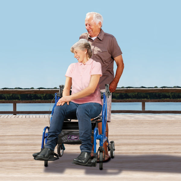 Drive AirGo Fusion 2-in-1 Rollator in use on a sunny boardwalk by the water, woman seated with man standing behind, side view.