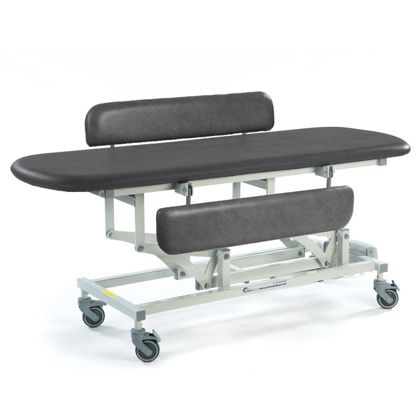 Black electric changing table with padded top, adjustable height, backrests and castor wheels, side view.