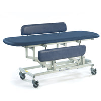 Sterling Electric Changing Table in dark blue with height adjustment, cushioned top, headrest, footrest and wheels, side view.