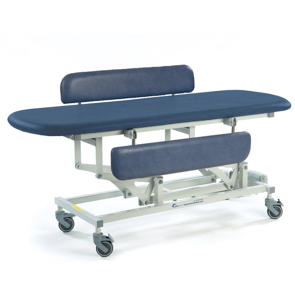 Sterling Electric Changing Table in dark blue with height adjustment, cushioned top, headrest, footrest and wheels, side view.