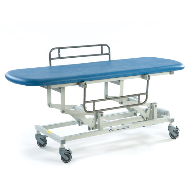 Sky blue SEERS Medical Sterling electric changing table with wheels and metal guard rail at one end, side view.