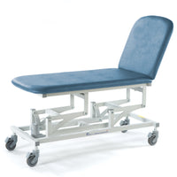 Sky blue two-section electric couch with height adjustment and wheels, designed for patient use, side view.