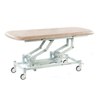 Cream hydraulic therapy hygiene table with white frame and caster wheels, height adjustable, clinical setting, side view.
