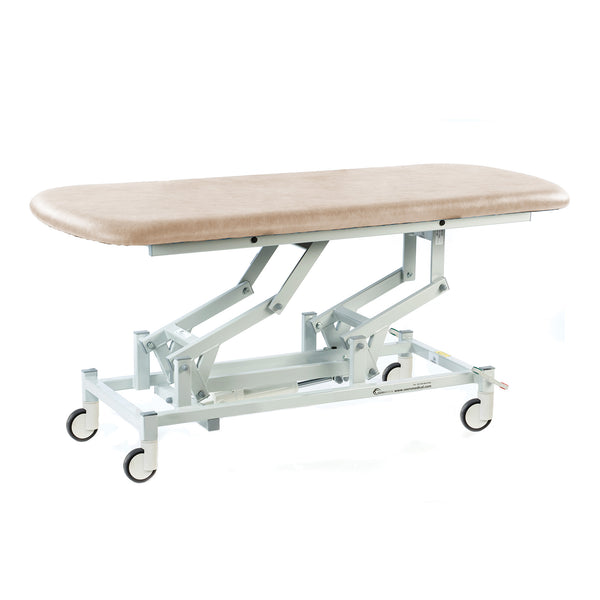 Cream hydraulic therapy hygiene table with white frame and caster wheels, height adjustable, clinical setting, side view.