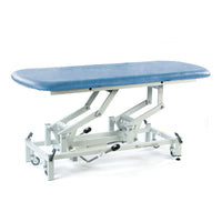 Sky blue SEERS Medical hydraulic therapy hygiene table with white frame, lockable castors, height adjustable, left side view.
