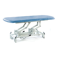 Sky blue hydraulic therapy hygiene table with scissor-lift frame and lockable casters, side view.
