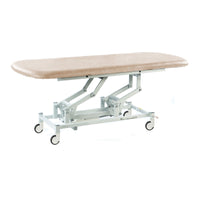 Cream-coloured hydraulic therapy hygiene table with height adjustment and caster wheels, shown in a side view.