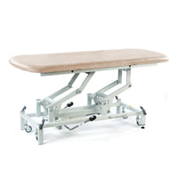 Cream hydraulic therapy hygiene table with height adjustment and wheels, shown in a side view.
