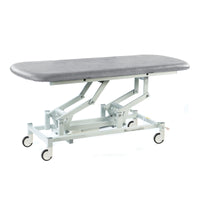 Light grey electric therapy hygiene table with height adjustment and wheels, white background, angled front view.