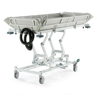 Hydraulic shower trolley with side rails, wheels, and drainage hoses for patient transport or bathing, side view.