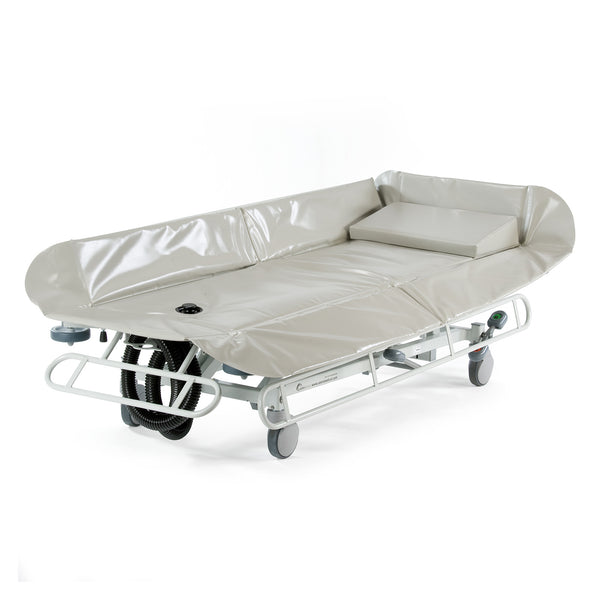 Grey padded hydraulic shower trolley with raised sides and wheels, waterproof surface, side angle.