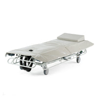 White hydraulic shower trolley with wheels, side rails, and headrest for patient care, shown in a side view.