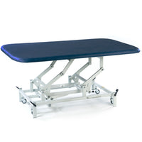 Dark blue SEERS Medical electric therapy mat table with height adjustment, white scissor-lift frame and wheels, side view.