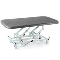 Hydraulic therapy mat table in dark grey with height adjustment and white wheeled frame, side view.