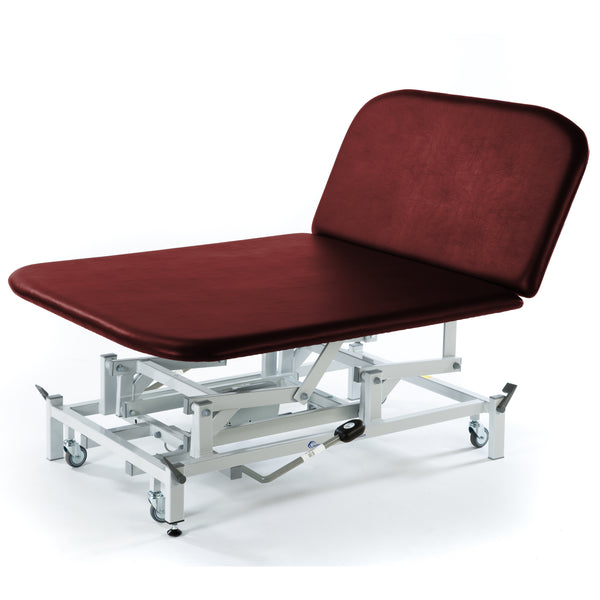 Burgundy SEERS Medical hydraulic therapy Bobath couch with metal frame and wheels, side view.