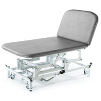 Light grey hydraulic therapy Bobath couch with padded top, metal frame and wheels for moving, side view.