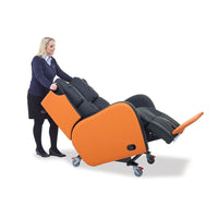 Black and orange Boston Healthcare Chair with wheels and pressure-relieving support, being pushed by a woman, side view in use.