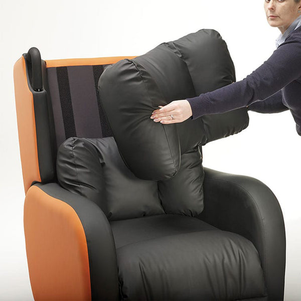 Large black cushion being placed on orange and black Boston Healthcare Chair, in use, side view.