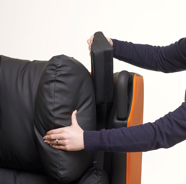 Removable armrest being adjusted on black and orange Boston Healthcare Chair, person shown, in use side view.