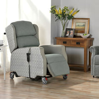Madison Healthcare Chair by Repose Seating with wheels, in a living room beside a table with flowers, photos and artwork, angled side view.