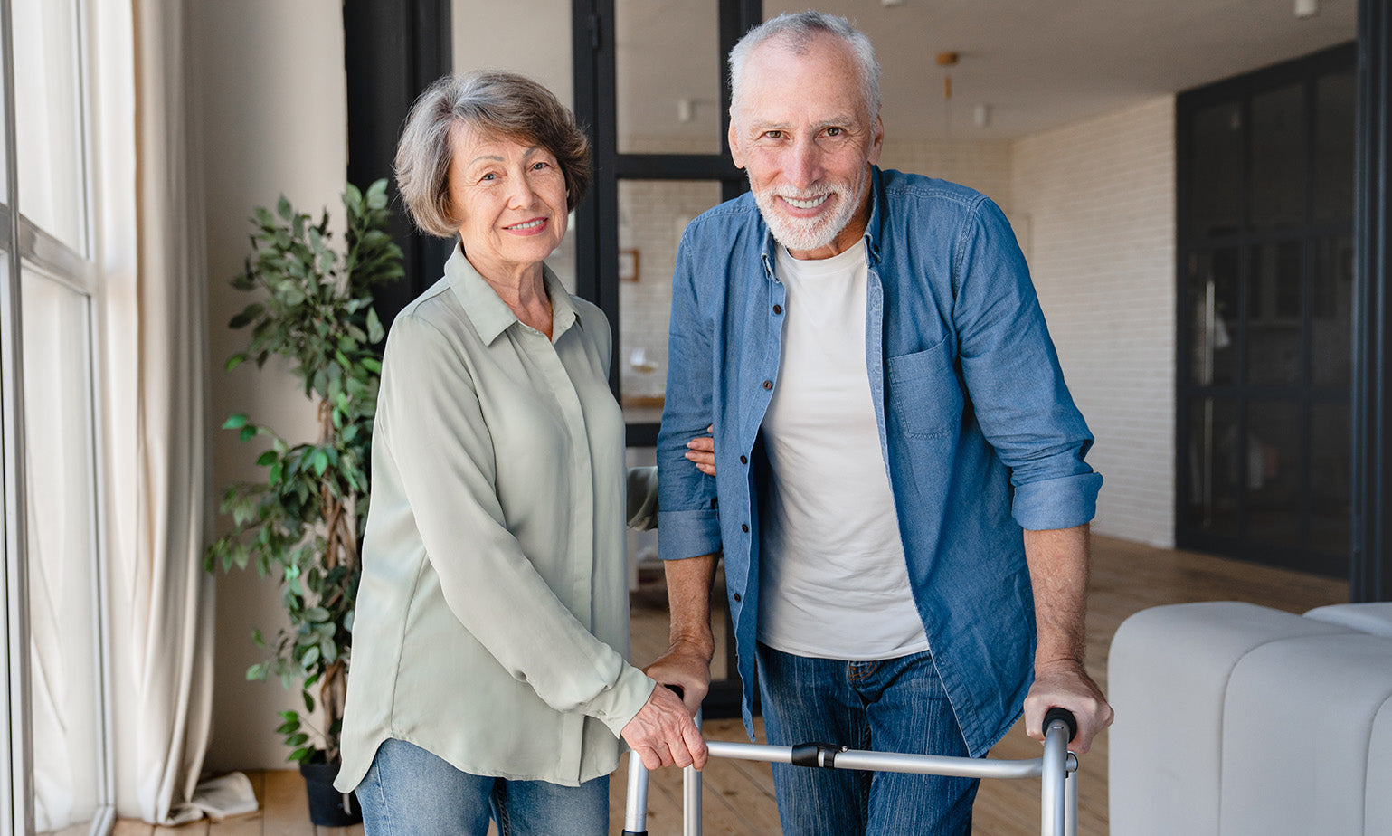 Senior couple with a woman holding a walker indoors.