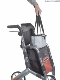 Trust Care Let’s Shop Rollator in black with storage compartments, shopping bags hanging from handle, in use angle.