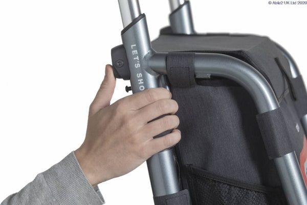 Trust Care Let’s Shop Rollator in black with a black fabric shopping bag, hand holding the handle, close-up view.