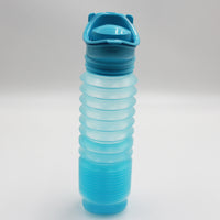 Buckingham Uriwell Unisex Urinal, collapsible plastic with textured grip and flip-top lid, upright on white background, front view.