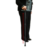 Person holding Lifemax Adjustable Walking Stick with dashed arrow highlighting non-slip rubber foot touching the floor, in use view.