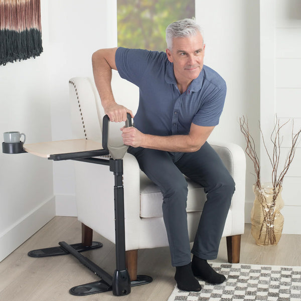 Stander Assist-A-Tray Over Chair Table with integrated support handle being used to stand from an armchair, in use.