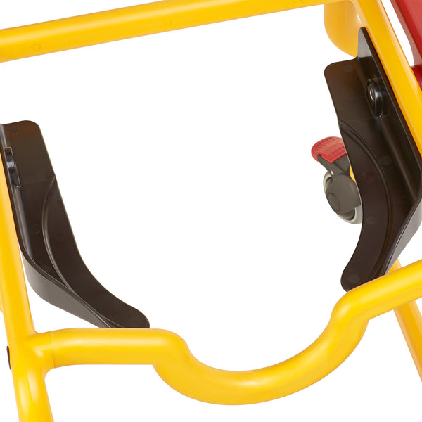 Childrens shower commode chair with yellow frame, black supports, red lever on wheel and adjustable footrest, close-up view.