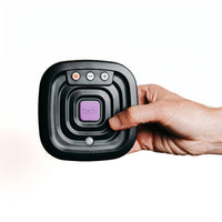 Hand holding Ravencourt Bide Fall Prevention Device with button, for older adults, white background, close-up.